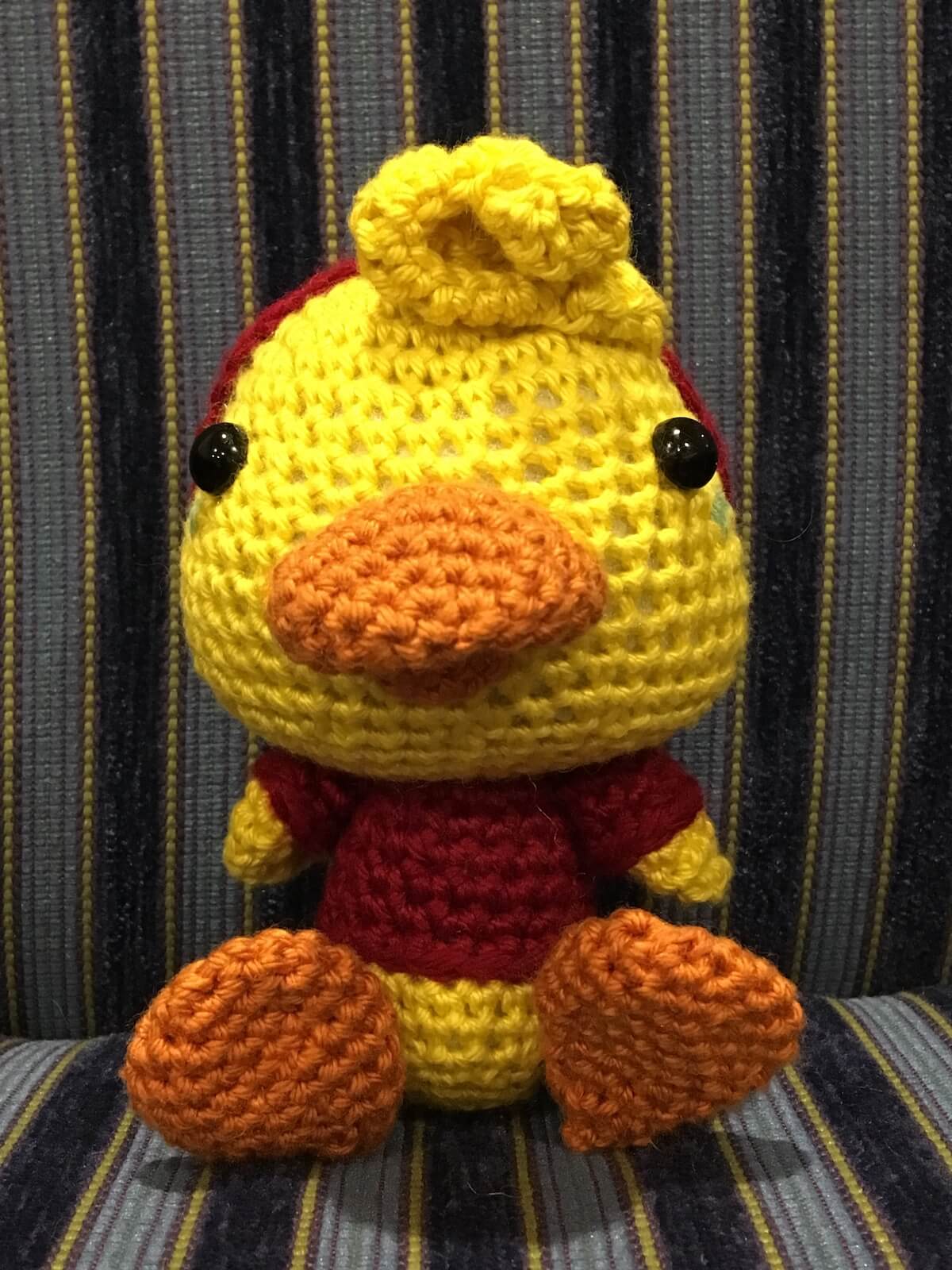 a yellow crochet duck with a red hoodie